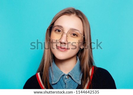 emotions, fashion, people, youth and beauty concept - Close up shot of stylish young woman in sunglasses smiling against gray background. Beautiful female model with copy space.