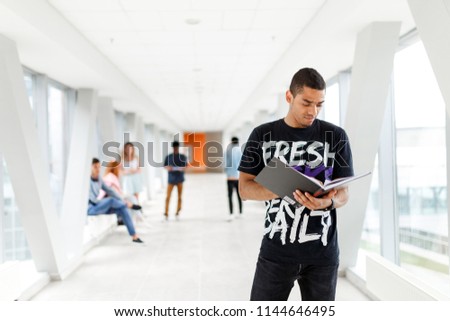 African-American student stands with a book at the University. Students in the background. The photo illustrates education, College, school, or University.
