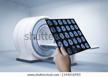 Hand holding x-ray film with 3d rendering mri scan machine or magnetic resonance imaging scan device
