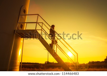 Girl standing on a stairs to windturbine during amazing sunset