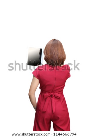 Back view of standing young beautiful woman in red dress with tablet computer in her hands on white background with path.