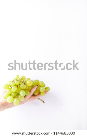 Hand holding green grapes on white background minimalism