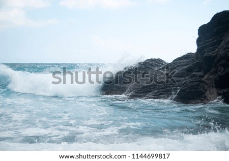 The powerful wave covers the rock. A seascape in summer. Place for tourists. Beautiful view of the marine element. Nice picture.