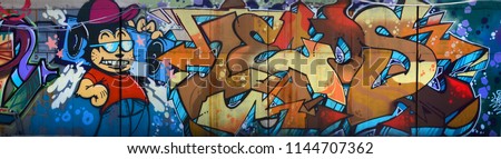 Street art. Abstract background image of a full completed graffiti painting in beige and orange tones with cartoon character Royalty-Free Stock Photo #1144707362