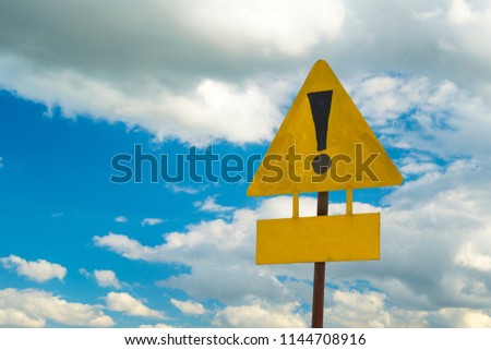 Exclamation point of attention on a yellow triangular sign with a sign for signing. Against the sky in the sunset. Warning, danger.