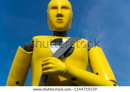 yellow crash test dummy statue on blue sky background
