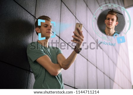 Face recognition. Biometric verification. The concept of a new face recognition technology on a polygonal mesh. Young modern guy with a smartphone in his hands. Young man with phone in hands.