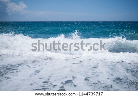Beautiful white waves are covering the sand in summer at a coast. Bright and colorful picture. Natural beauty. 