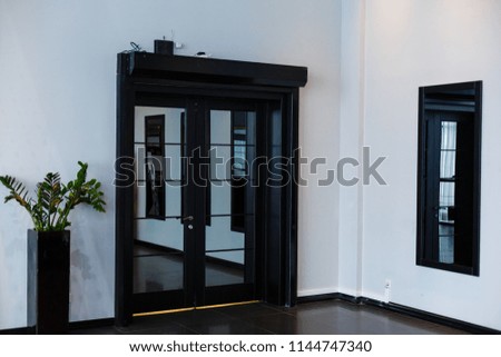 Corner room with a wooden wall, an aged floor, black glass doors and dressing mirror