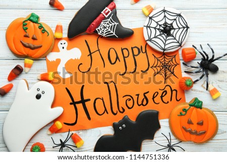 Halloween gingerbread cookies with candies and inscription on orange paper