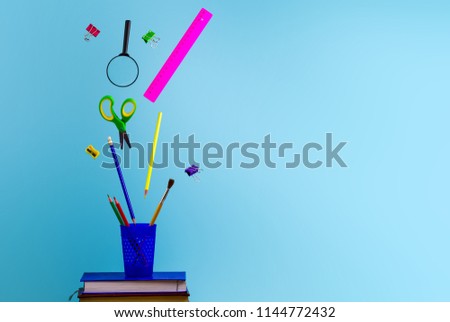 Flying school supplies on a blue background. School concept. Copy space