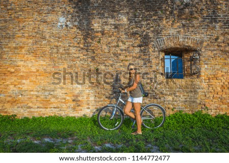 Woman riding bike in front of a beautiful brick wall