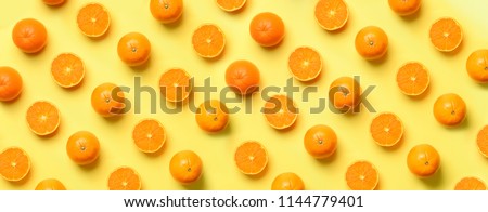 Fruit pattern of fresh orange slices on yellow background. Top view. Copy Space. Pop art design, creative summer concept. Half of citrus in minimal flat lay style. Banner