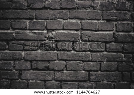 Black and white photo of the old grey exterior wall with lines of concrete between rectangle shabby bricks