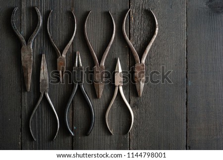 old pliers on black wood background directly above