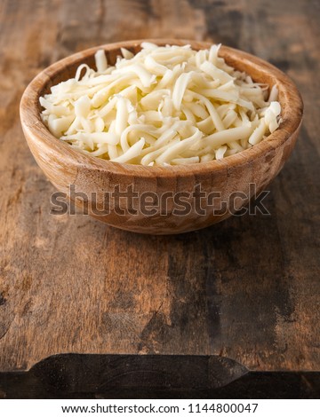 heap of grated mozzarella cheese in wooden bowl  Royalty-Free Stock Photo #1144800047