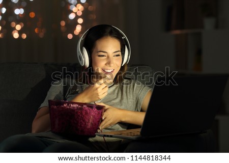 Single woman watching online tv in the night sitting on a couch in the living room at home Royalty-Free Stock Photo #1144818344