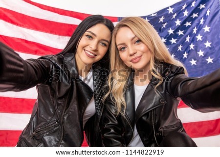 american and rissian friendship.glamour girls having selfie time. close up portrait. national flag on the background of the photo