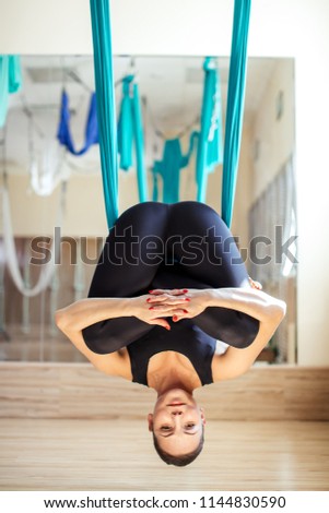 fit girl in funny pose of antigravity yoga. close up full length photo