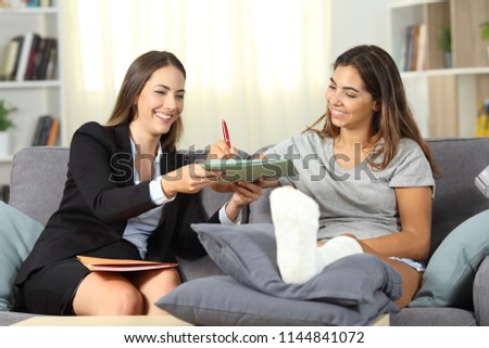 Disabled woman signing a contract with a insurance agent sitting on a couch in the living room at home Royalty-Free Stock Photo #1144841072
