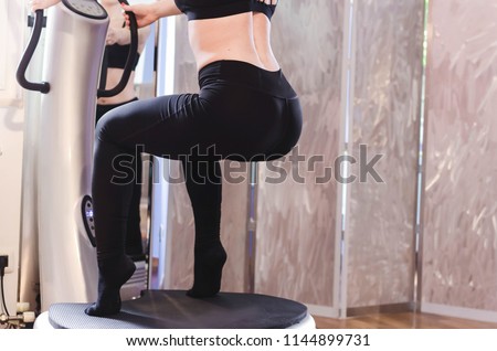 Cropped image of young woman doing squats on power plate. Royalty-Free Stock Photo #1144899731