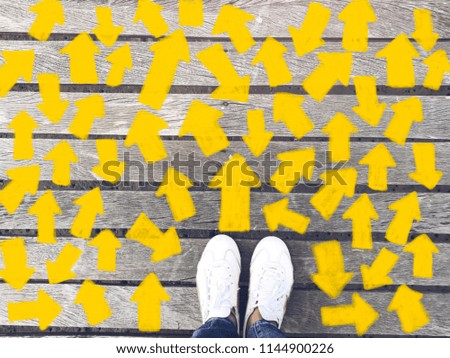 Top view of selfie feet on wooden floor background with yellow drawn many direction arrows , decision making , Choices concept, where to go, directions, business solutions