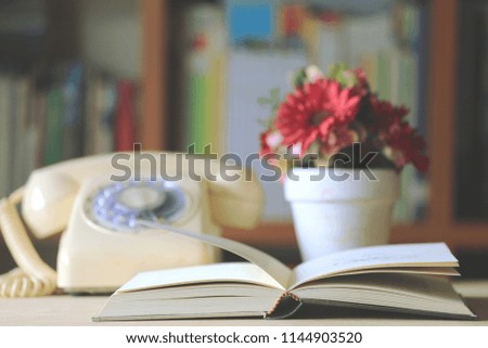 Close-up of books opened on library table old antique telephone with flower pot is the background selective focus and shallow depth of field