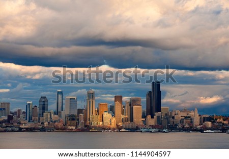 Seattle Skyline After A Rain Squall. Dramatic clouds surround the city of Seattle and the vibrant waterfront with modern skyscrapers looming large in the background.