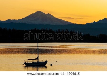 Sailboat Anchored in the Salish Sea with Mt. Baker in the Background. Sunrise in Hales Pass near Lummi Island, Washington with Mt. Baker looming large in the background.