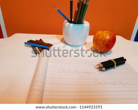 Calligraphy notebook and pictures of school supplies, crayons, crayons and black pencil