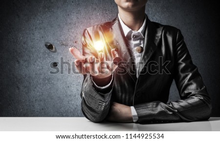 Businessman in suit presenting glowing solar system in his hands with gray wall on background. 3D rendering.