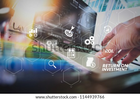 ROI Return on Investment indicator in virtual dashboard for improving business. business man hand working on laptop computer with digital business strategy diagram on wooden desk as concept