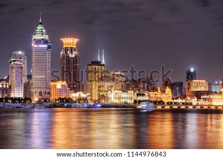 Amazing night view of Puxi skyline in Shanghai, China. Modern and old buildings of the Bund (Waitan) at historic center. Colorful city lights reflected in water of the Huangpu River.