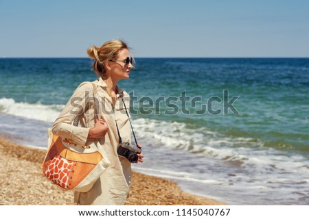 A young woman on a walk by the sea with an old camera
