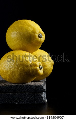 Three ripe lemons on old wooden boards on a black background. Shooting in the style of "dark mood".