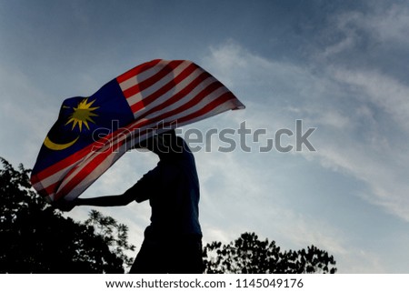 Independence Day concept. A happy and proud citizen holding and waving Malaysian flag. sky background.