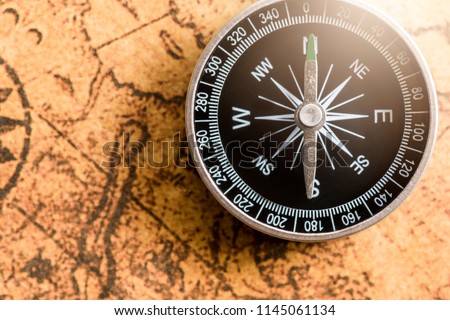Close up of old black compass on ancient map background ,vintage tone with copy space for text.