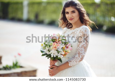 A beautiful bride in a white wedding dress and with a bouquet of flowers enjoying the moment. Wonderful mood, beautiful waves, great atmosphere. wedding concept