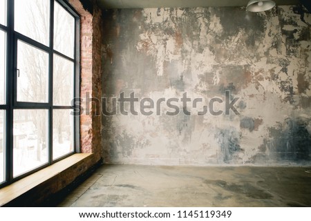 
A huge window to the floor on the entire concrete wall with a wooden window sill. Loft industrial grunge interior. Brick and dark background. Place for text Royalty-Free Stock Photo #1145119349