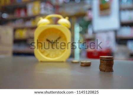 Yellow alarm clock and fingers of business man putting on coin and looking for saving money, collect money with earning bank deposit interest and take time. Business ideas concept. Selective focus.
