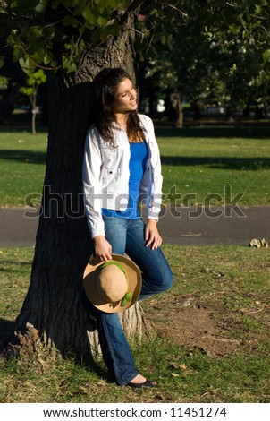 The girl with a hat near a tree in park