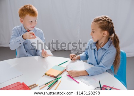 portrait of cute preschoolers drawing pictures at table with in classroom
