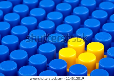 In the picture a bunch of blue plastic blocks and one yellow.