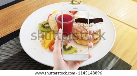 Taking food photo, dessert photography by smart phone,Hands with the phone close-up pictures of food. Breakfast homemade. girls take food photos on the phone a smartphone sweet Pancake with fruit.