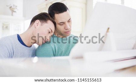 Portrait of male couple in love sitting a piano as one of them play
