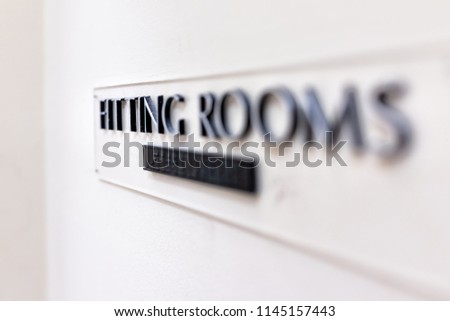 Closeup of Fitting Room sign in mall store shop retail clothing changing door entrance with nobody on wall, braille