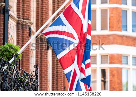 Closeup of row of national flags hanging on balcony in London, UK, United Kingdom, Great Britain on wall of building, poles historic architecture