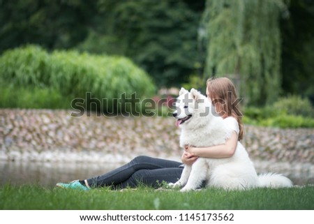 Samoyed dog and girl posing in the park. True friends together.
