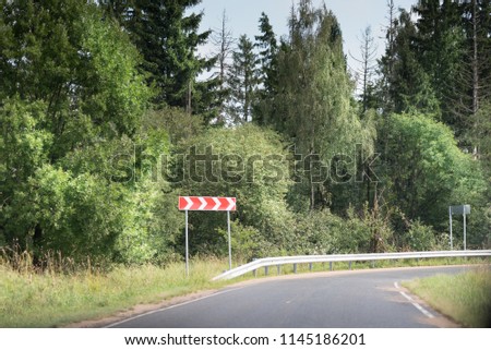 Road sign warning sign for turn right. metal safety barrier. Forest road with asphalt