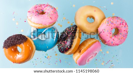 flying doughnuts scene - mix of multicolored sweet donuts with sprinkel on blue background Royalty-Free Stock Photo #1145198060